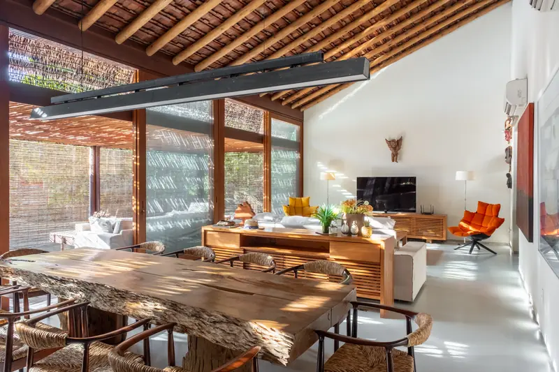 Sala de estar e jantar integradas, com mesa de madeira maciça e teto de madeira