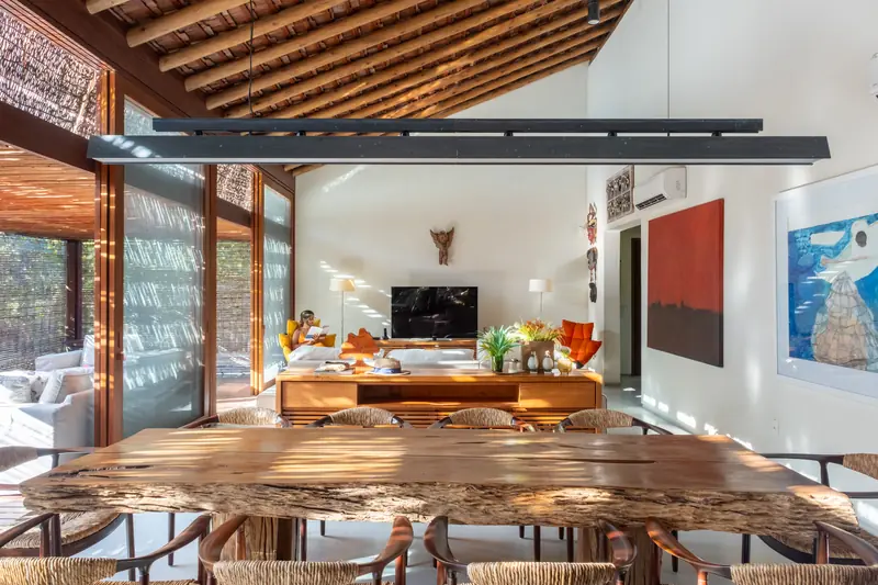 Mesa de jantar de madeira com a sala de estar ao fundo