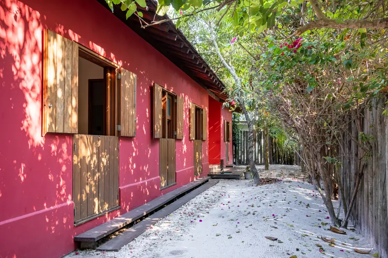 Fachada vermelha com janelas de madeira, junto ao jardim