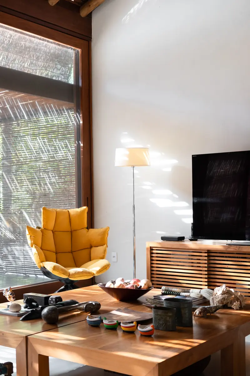 Sala com poltrona, TV e mesa de madeira