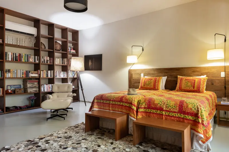 Suíte com cama, estante de livros e poltrona